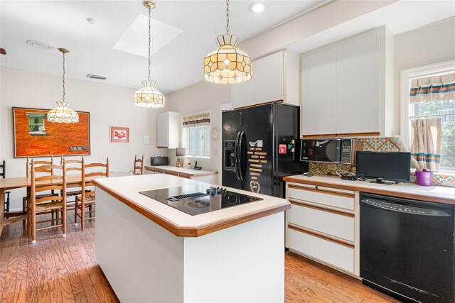 1671 S Dr, Sarasota, FL 34239 - kitchen with black appliances, light wood-style floors, white cabinetry, light countertops, and decorative light fixtures