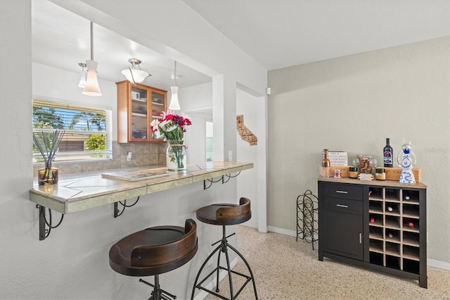 1324 Augusta Ln S, Saint Petersburg, FL 33707 - bar area featuring dark aggregate flooring, decorative backsplash, baseboards, pendant lighting, and a textured wall