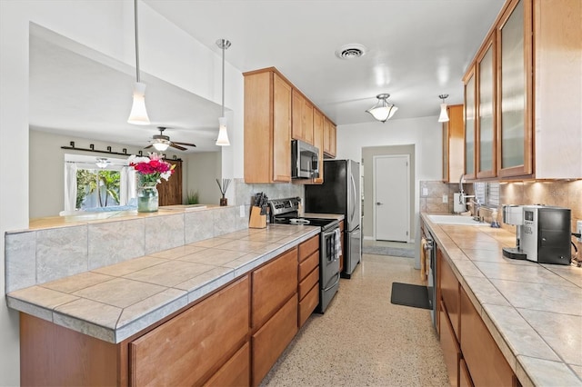 1324 Augusta Ln S, Saint Petersburg, FL 33707 - kitchen with stainless steel appliances, backsplash, glass insert cabinets, a ceiling fan, and a peninsula