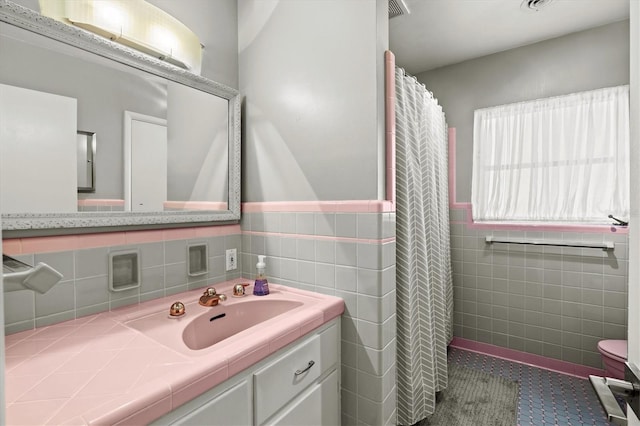 1324 Augusta Ln S, Saint Petersburg, FL 33707 - full bathroom featuring tile walls, vanity, tile patterned flooring, toilet, and a wainscoted wall