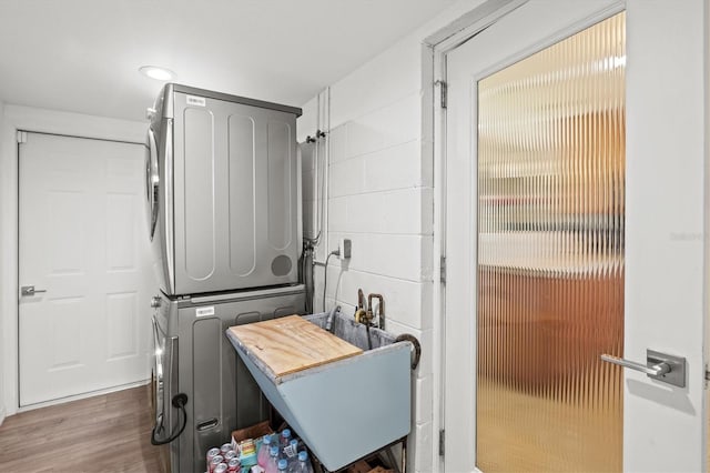 1324 Augusta Ln S, Saint Petersburg, FL 33707 - laundry area featuring stacked washing machine and dryer and wood finished floors