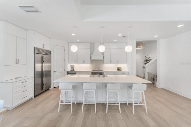 8069 Tidal Pointe Way, Sarasota, FL 34240 - kitchen featuring stainless steel built in refrigerator, custom range hood, light wood-type flooring, light countertops, and white cabinetry
