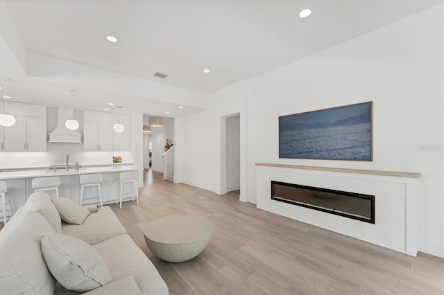 8069 Tidal Pointe Way, Sarasota, FL 34240 - living area featuring light wood finished floors, a glass covered fireplace, recessed lighting, and baseboards