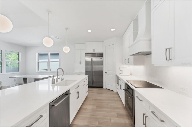 8069 Tidal Pointe Way, Sarasota, FL 34240 - kitchen featuring black appliances, a sink, custom range hood, light wood finished floors, and light countertops