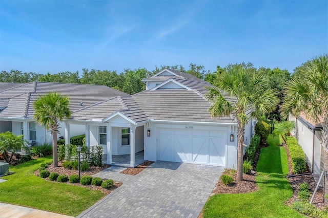 8069 Tidal Pointe Way, Sarasota, FL 34240 - ranch-style home featuring a garage, a tiled roof, decorative driveway, a front yard, and stucco siding