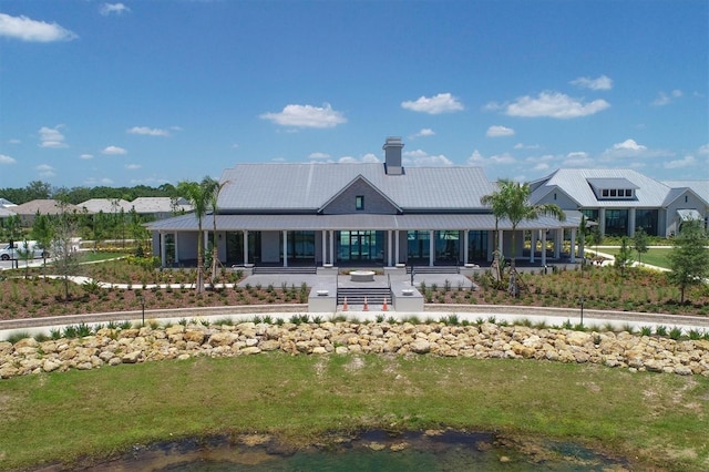 8069 Tidal Pointe Way, Sarasota, FL 34240 - rear view of property featuring a porch, a yard, metal roof, and a chimney