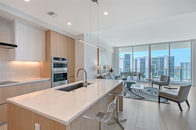 301 Quay Commons Unit 1208, Sarasota, FL 34236 - kitchen with a sink, modern cabinets, stainless steel double oven, an island with sink, and plenty of natural light