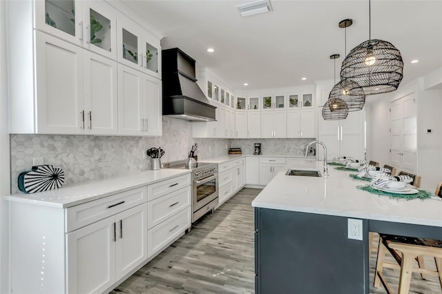 5219 Calle Menorca, Sarasota, FL 34242 - kitchen with stainless steel electric stove, a sink, premium range hood, light countertops, and a breakfast bar area