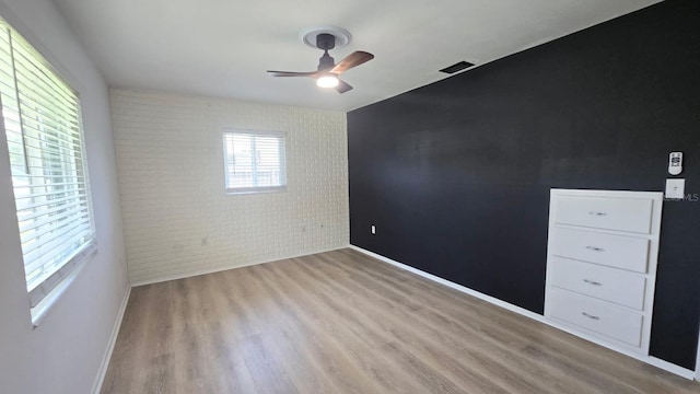 3730 Ferguson St, Sarasota, FL 34233 - spare room with a ceiling fan, light wood finished floors, an accent wall, baseboards, and brick wall