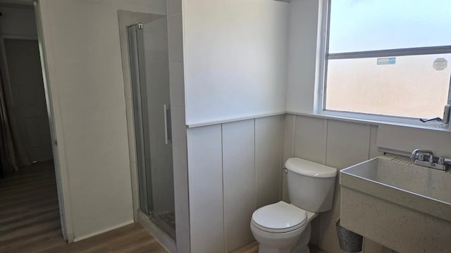 3730 Ferguson St, Sarasota, FL 34233 - full bathroom with a stall shower, wood finished floors, toilet, a sink, and a wainscoted wall