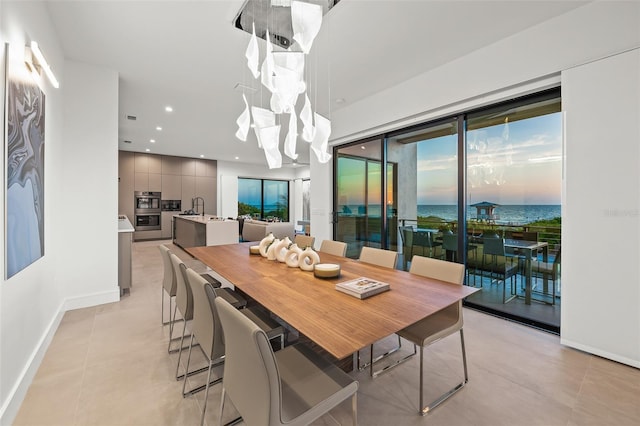 100 6th St S, Bradenton Beach, FL 34217 - dining space with baseboards, a chandelier, recessed lighting, light tile patterned floors, and a water view
