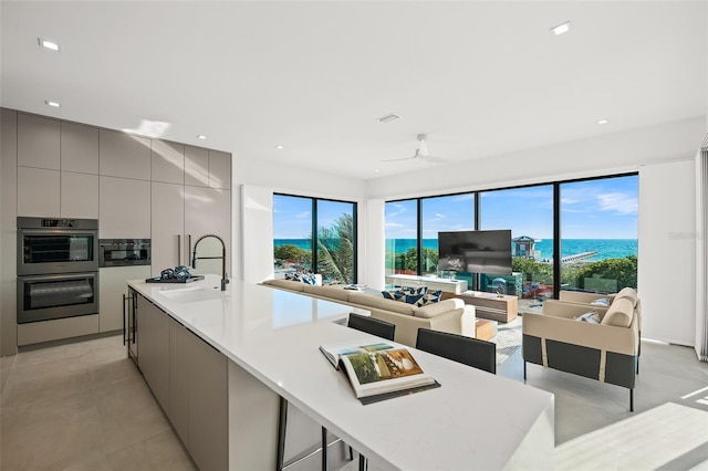 100 6th St S, Bradenton Beach, FL 34217 - kitchen with gray cabinetry, modern cabinets, a sink, stainless steel double oven, and a large island