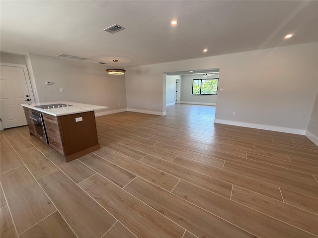 808 25th Ave W, Palmetto, FL 34221 - kitchen featuring stainless steel oven, open floor plan, black electric cooktop, light wood finished floors, and light countertops