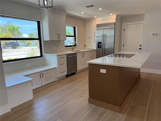 808 25th Ave W, Palmetto, FL 34221 - kitchen featuring appliances with stainless steel finishes, a sink, light stone countertops, a kitchen island, and recessed lighting