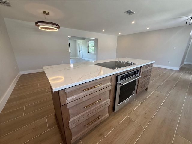 808 25th Ave W, Palmetto, FL 34221 - kitchen with oven, black electric stovetop, wood finish floors, baseboards, and a center island