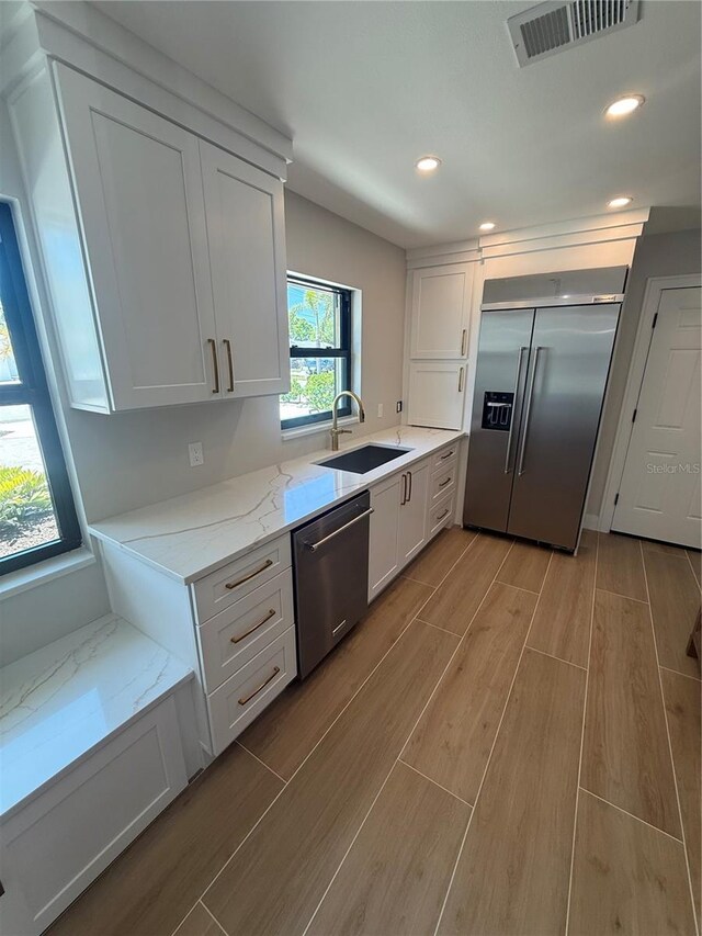 808 25th Ave W, Palmetto, FL 34221 - kitchen with appliances with stainless steel finishes, a sink, light wood finished floors, white cabinetry, and recessed lighting
