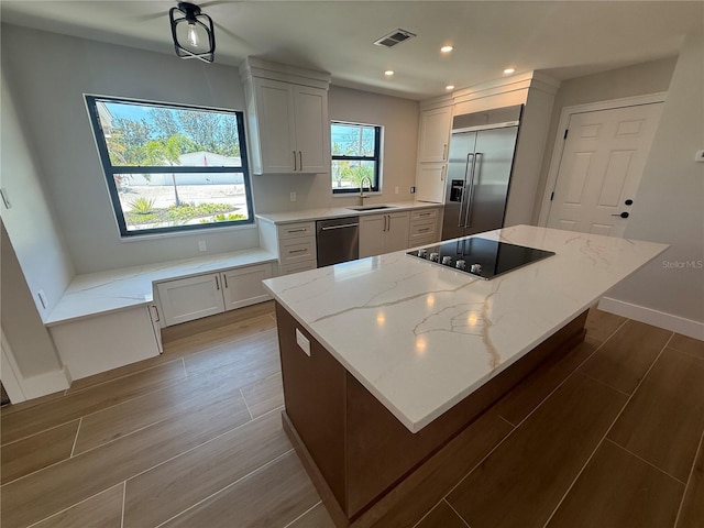 808 25th Ave W, Palmetto, FL 34221 - kitchen with appliances with stainless steel finishes, wood finished floors, a center island, recessed lighting, and light stone counters