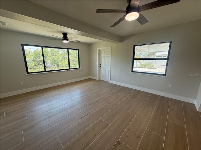 808 25th Ave W, Palmetto, FL 34221 - empty room with ceiling fan, healthy amount of natural light, wood finished floors, and baseboards