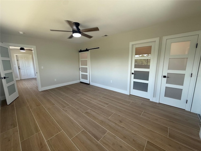 808 25th Ave W, Palmetto, FL 34221 - empty room with ceiling fan, a barn door, wood finished floors, and baseboards