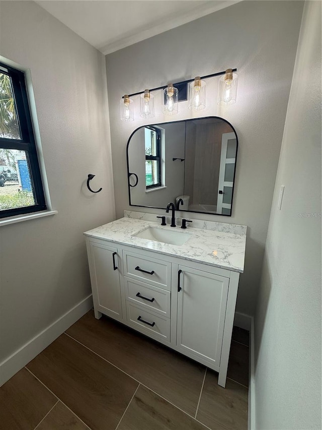 808 25th Ave W, Palmetto, FL 34221 - bathroom featuring vanity, wood finished floors, healthy amount of natural light, and baseboards