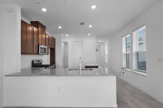 8632 Snowfall St, Sarasota, FL 34241 - kitchen with stainless steel appliances, a peninsula, light stone countertops, and recessed lighting