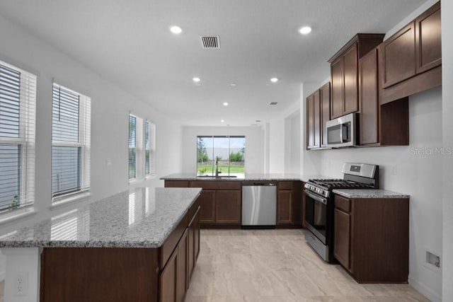8632 Snowfall St, Sarasota, FL 34241 - kitchen featuring stainless steel appliances, a peninsula, light stone counters, recessed lighting, and dark brown cabinets