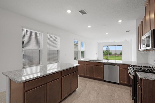 8632 Snowfall St, Sarasota, FL 34241 - kitchen featuring appliances with stainless steel finishes, a peninsula, light stone counters, recessed lighting, and a center island