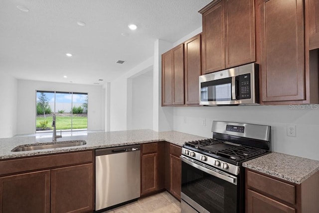 8632 Snowfall St, Sarasota, FL 34241 - kitchen with stainless steel appliances, light stone countertops, recessed lighting, and a peninsula