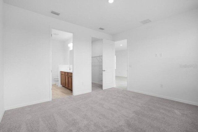 8632 Snowfall St, Sarasota, FL 34241 - unfurnished bedroom with a spacious closet, light colored carpet, recessed lighting, a closet, and connected bathroom