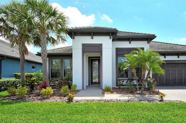 1919 Woodleaf Hammock Ct, Bradenton, FL 34211 - view of exterior entry featuring a tile roof, an attached garage, decorative driveway, stucco siding, and a yard