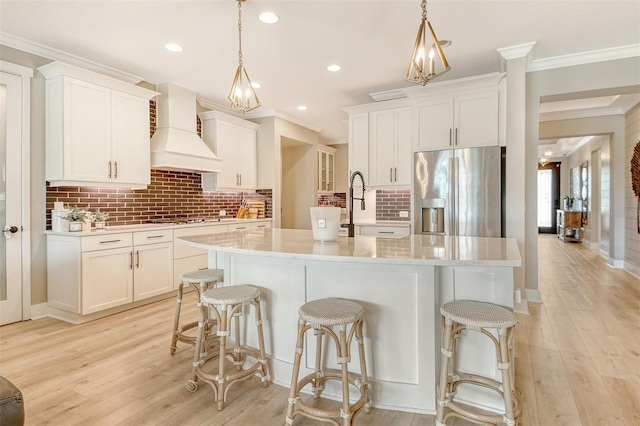 1919 Woodleaf Hammock Ct, Bradenton, FL 34211 - kitchen featuring stainless steel fridge with ice dispenser, custom range hood, crown molding, decorative backsplash, and an island with sink