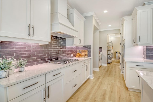 1919 Woodleaf Hammock Ct, Bradenton, FL 34211 - kitchen featuring premium range hood, stainless steel gas cooktop, crown molding, white cabinetry, and tasteful backsplash