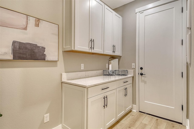 1919 Woodleaf Hammock Ct, Bradenton, FL 34211 - kitchen with light wood-style flooring, light stone counters, white cabinetry, and baseboards
