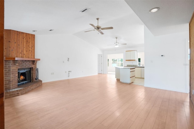 5639 Blount Ave, Sarasota, FL 34231 - unfurnished living room featuring ceiling fan, lofted ceiling, baseboards, a fireplace, and light wood-style floors
