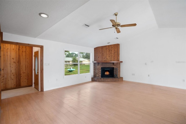 5639 Blount Ave, Sarasota, FL 34231 - unfurnished living room featuring vaulted ceiling, ceiling fan, light wood finished floors, a brick fireplace, and baseboards