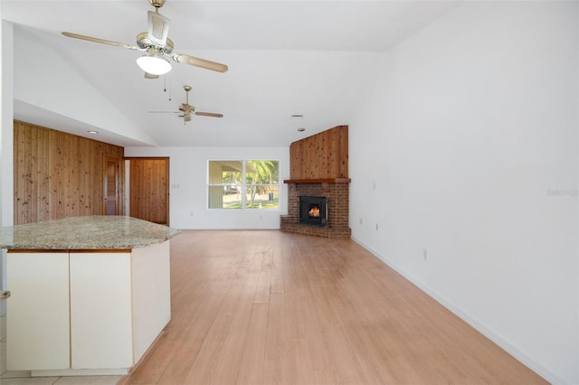 5639 Blount Ave, Sarasota, FL 34231 - unfurnished living room with vaulted ceiling, ceiling fan, light wood-type flooring, a brick fireplace, and wooden walls
