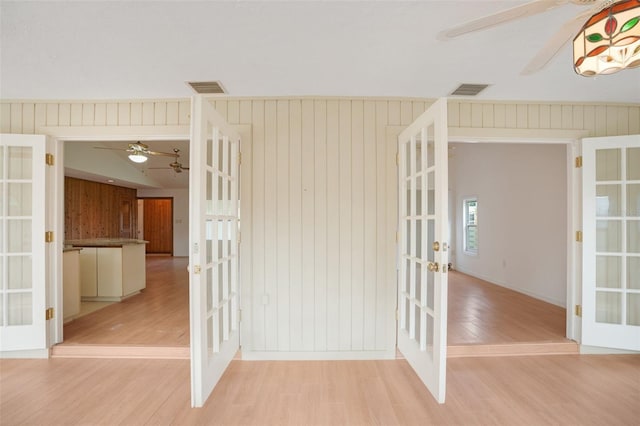 5639 Blount Ave, Sarasota, FL 34231 - empty room with french doors, a ceiling fan, light wood-type flooring, and wood walls