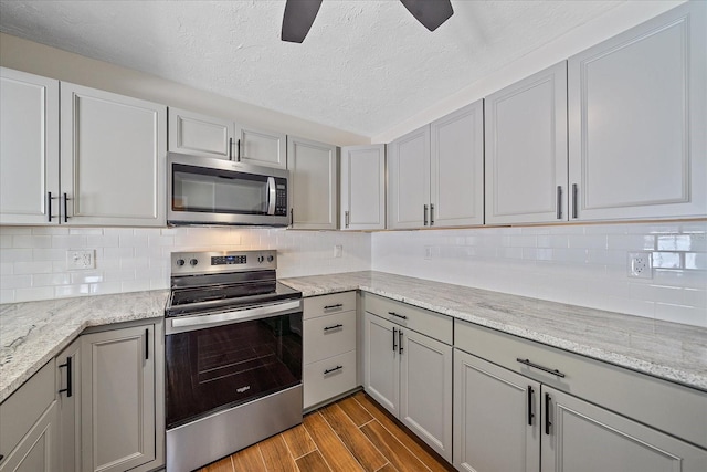 2953 Oak St, Sarasota, FL 34237 - kitchen with appliances with stainless steel finishes, dark wood-type flooring, a textured ceiling, ceiling fan, and backsplash