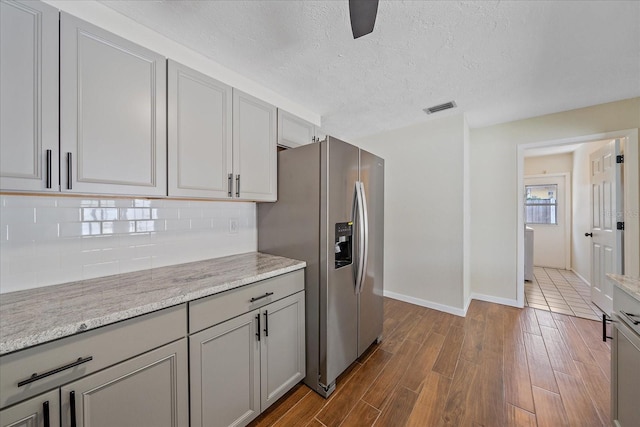 2953 Oak St, Sarasota, FL 34237 - kitchen with stainless steel fridge, gray cabinets, decorative backsplash, dark wood finished floors, and baseboards
