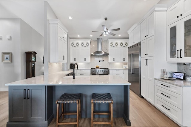 4844 14th Ave E, Bradenton, FL 34208 - kitchen with high quality appliances, wall chimney range hood, a peninsula, ceiling fan, and white cabinets