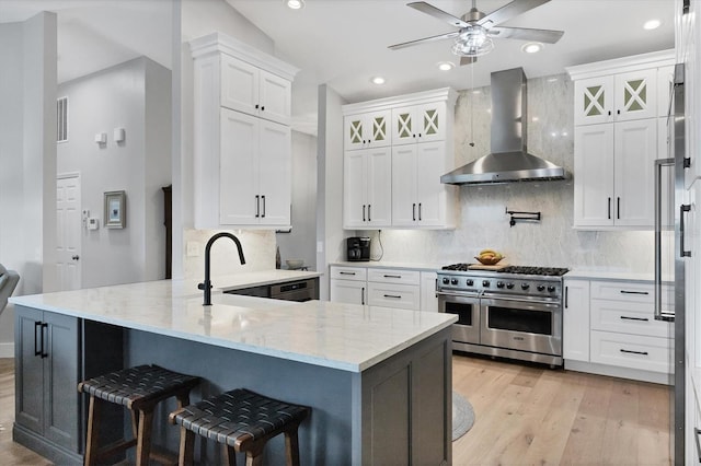 4844 14th Ave E, Bradenton, FL 34208 - kitchen featuring wall chimney range hood, range with two ovens, a peninsula, light wood-style floors, and recessed lighting