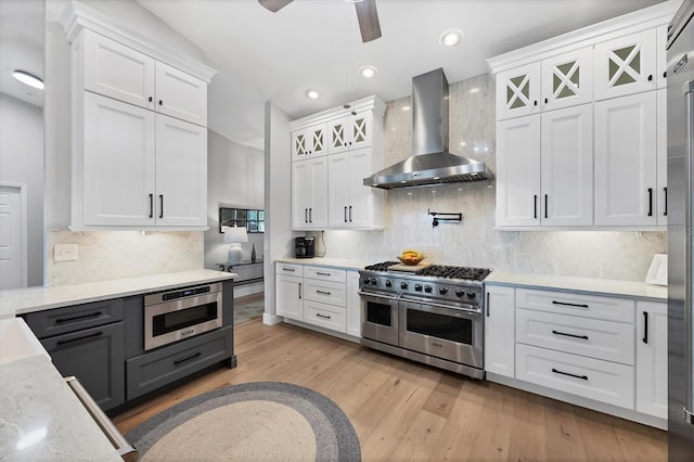 4844 14th Ave E, Bradenton, FL 34208 - kitchen with wall chimney range hood, double oven range, white cabinets, light wood finished floors, and recessed lighting