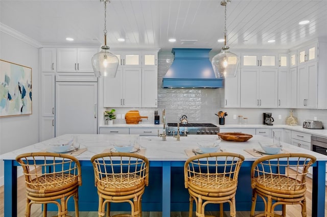 135 Avenida Veneccia, Sarasota, FL 34242 - kitchen featuring wall chimney range hood, white cabinetry, light stone countertops, backsplash, and recessed lighting