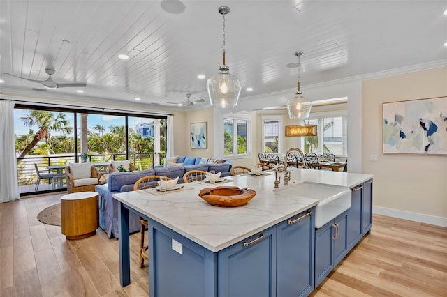 135 Avenida Veneccia, Sarasota, FL 34242 - kitchen with blue cabinets, open floor plan, crown molding, light wood-type flooring, and an island with sink