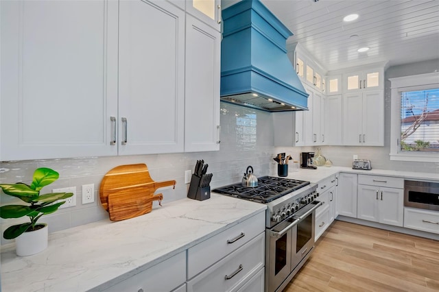 135 Avenida Veneccia, Sarasota, FL 34242 - kitchen with double oven range, custom range hood, white cabinetry, light stone counters, and recessed lighting