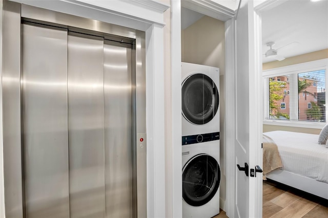 135 Avenida Veneccia, Sarasota, FL 34242 - laundry room with stacked washer and clothes dryer, elevator, and light wood-type flooring