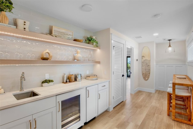 135 Avenida Veneccia, Sarasota, FL 34242 - bar area with wine cooler, tasteful backsplash, light wood-style flooring, pendant lighting, and a wainscoted wall
