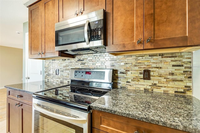 4375 Tortoise Rd, Venice, FL 34293 - kitchen featuring stainless steel appliances, dark stone counters, backsplash, light tile patterned floors, and brown cabinetry