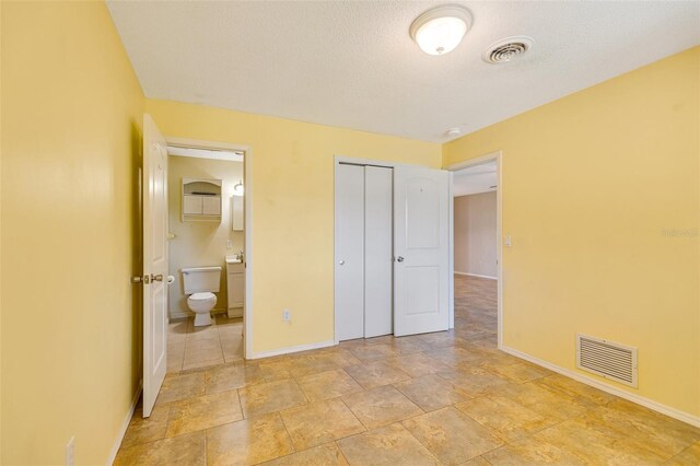 4375 Tortoise Rd, Venice, FL 34293 - unfurnished bedroom featuring baseboards, connected bathroom, a closet, and light stone finish flooring