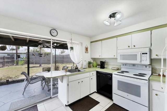 4535 Maceachen Blvd, Sarasota, FL 34233 - kitchen with white appliances, a sink, light countertops, light tile patterned floors, and white cabinets